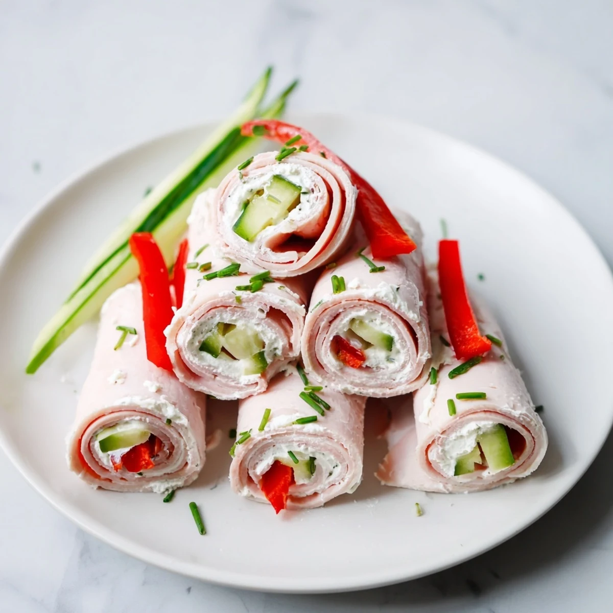 Stack of colorful turkey roll-ups, filled with cream cheese and crunchy veggies, ready to enjoy.