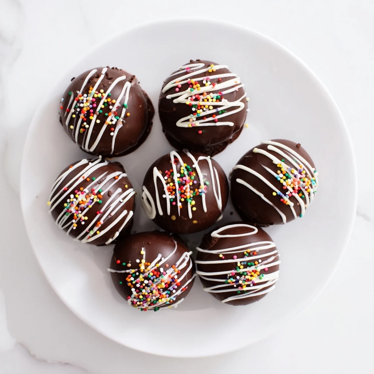 Decadent chocolate sphere hot cocoa bombs on a rustic wooden board, with cocoa powder and mini marshmallows visible inside the cracked shell.