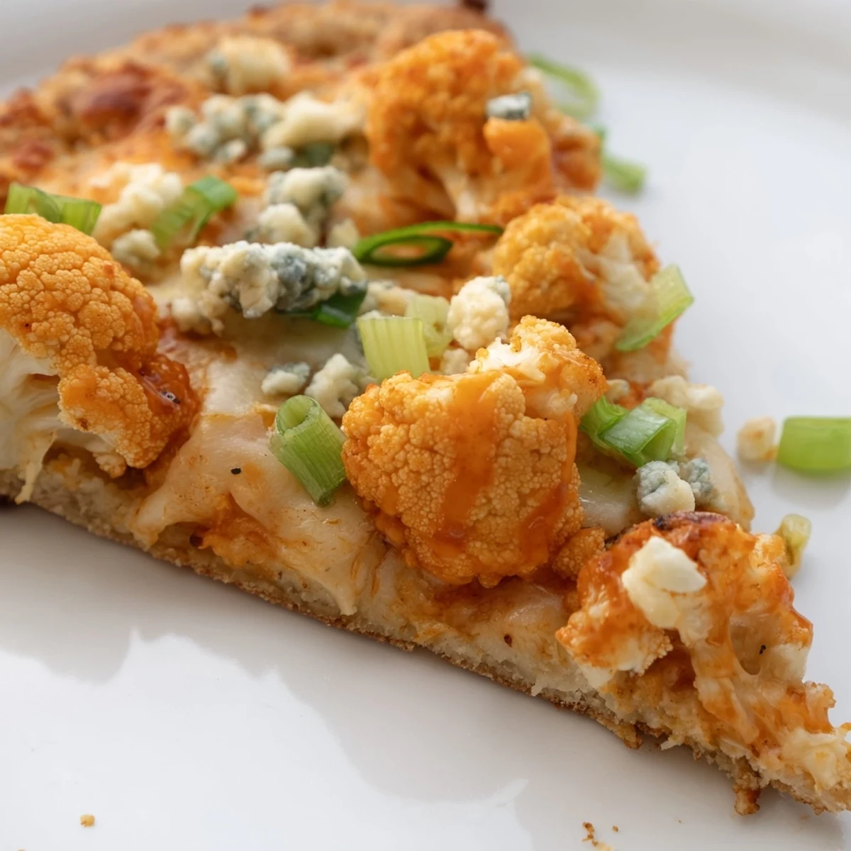 Sizzling Buffalo Cauliflower Pizza fresh from the oven, featuring a crispy golden crust topped with spicy sauce, melted mozzarella, and fresh green onions.
