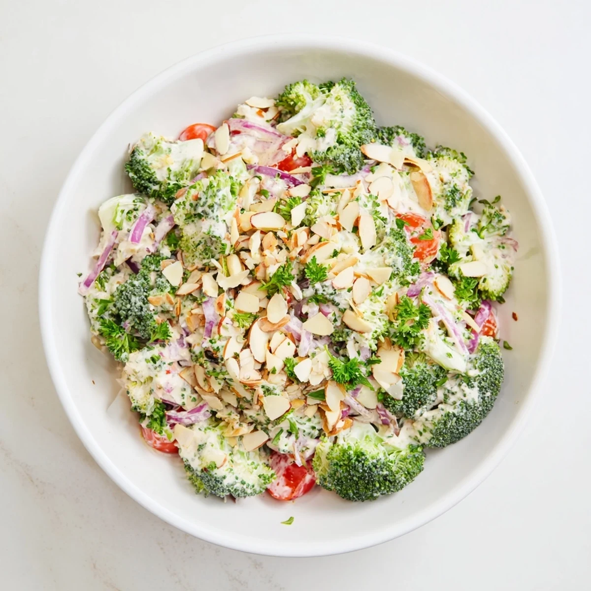 Fresh, crisp Garlic Parmesan Broccoli Salad in a white bowl with creamy dressing and toasted almond slivers.