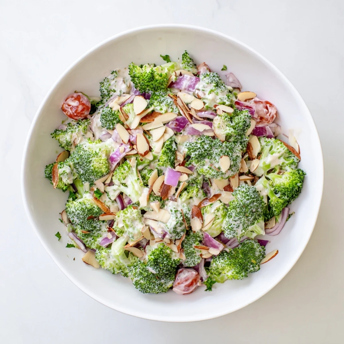 Garlic Parmesan Broccoli Salad with bright green florets, red onion, cherry tomatoes, and a sprinkle of Parmesan.