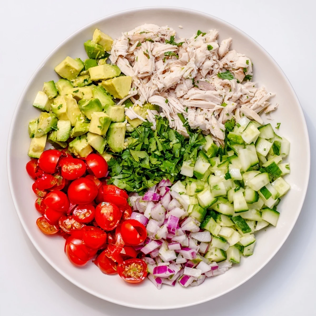 Freshly prepared Avocado Chicken Salad with shredded chicken, herbs, and olive oil, served in a rustic white bowl for a delicious gluten-free dinner.