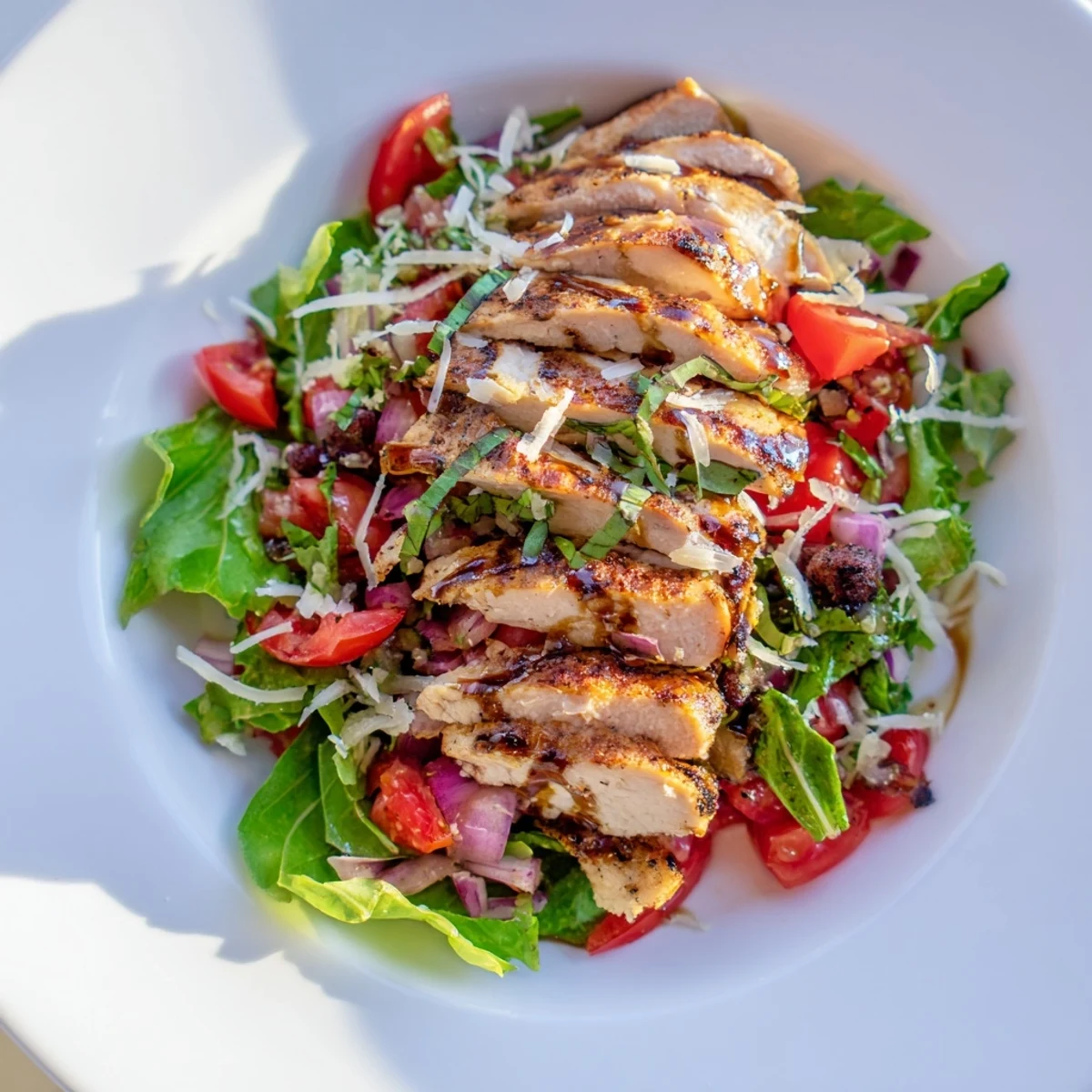 Sliced grilled chicken on mixed greens topped with fresh tomato-basil bruschetta and shaved Parmesan for a light Italian-American dinner.