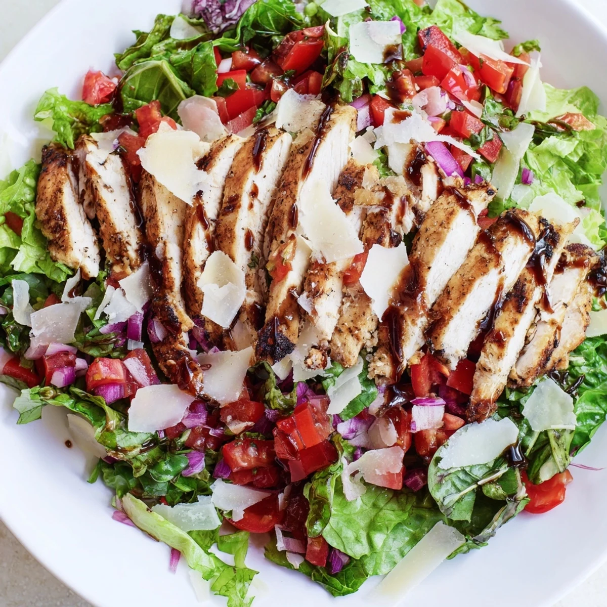 Juicy grilled chicken breast layered over crisp salad greens with a balsamic-tossed tomato bruschetta topping, ready to enjoy immediately.