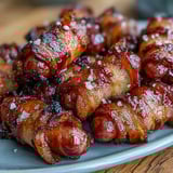 Toothpick-ready Bacon-Wrapped Smokies appetizers, featuring smoky sausages tightly wrapped in crunchy, caramelized bacon strips. 