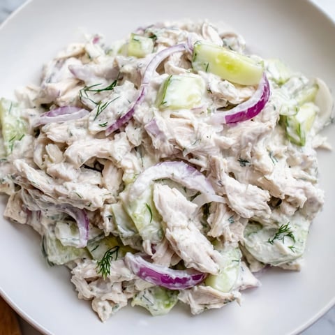 A close-up of Creamy Cucumber Chicken Salad with tender chicken, crisp cucumber slices, and fresh dill garnish on a white plate.