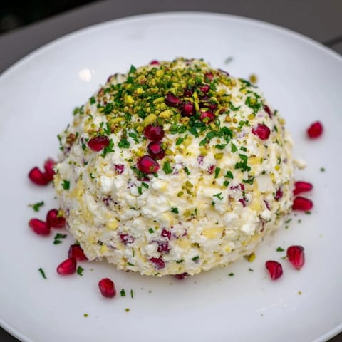 Festive Royal Orb cheese ball featuring creamy cheeses, vibrant pomegranate seeds, and crunchy pistachios: delicious!