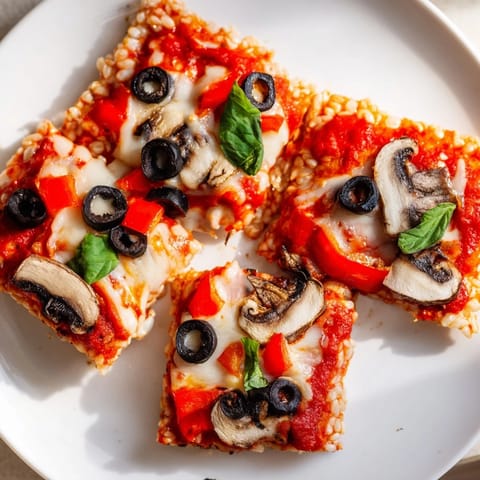 Mouthwatering image of Rice Cake Pizza Squares topped with fresh basil, steaming gently.