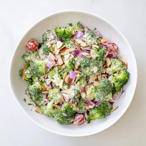 Garlic Parmesan Broccoli Salad with bright green florets, red onion, cherry tomatoes, and a sprinkle of Parmesan.