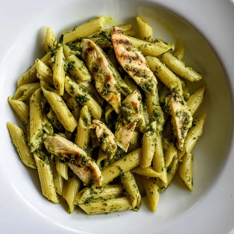 A close-up of Chimichurri Chicken Pasta highlights glossy, herb-speckled sauce coating every noodle and tender, smoky chicken pieces.