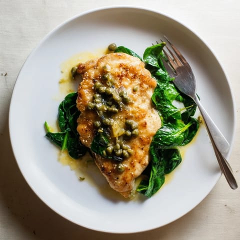 Pan-seared Spinach Lemon Butter Chicken, garnished with fresh parsley and lemon slices, resting on a rustic white plate.  