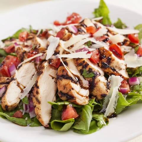 Bruschetta Chicken Salad served with lemon wedges on the side, highlighting vibrant red tomatoes, green basil, and golden sear marks.