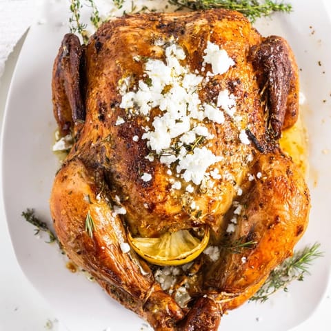 A close-up of roasted chicken with lemon herbs, tender potatoes, and creamy feta, ready to serve for a Mediterranean family dinner.  