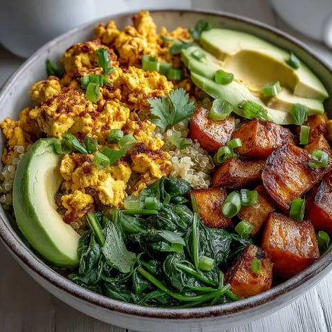 A hearty bowl of Tofu Scramble Vegan Breakfast Bowl with fluffy quinoa and vibrant sautéed spinach garnish.